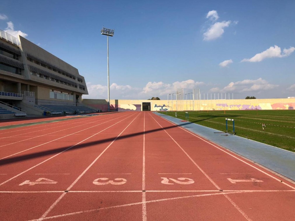 Straight view of running track lanes marked for sprints, with field area in the distance