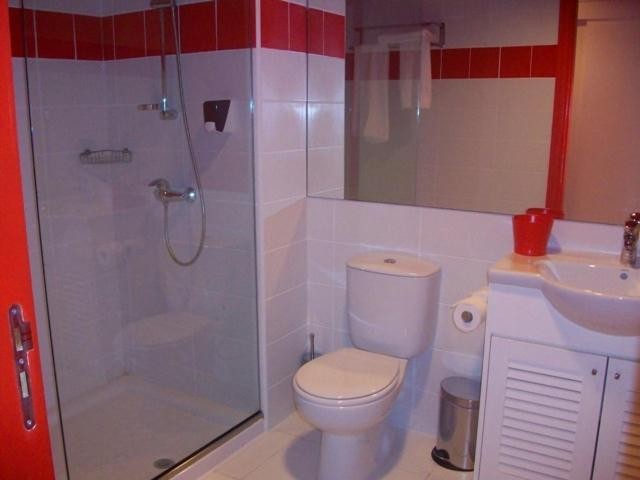 Compact bathroom with walk-in shower, white fixtures, and red tile accents