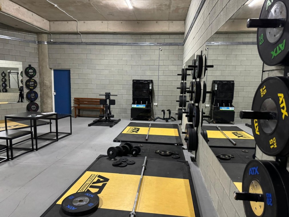 Strength training facility with barbells, weight plates, and racks for athlete conditioning exercises
