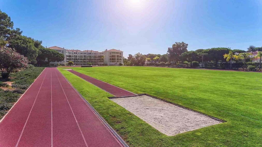 Athletics track with long-jump sand pit beside a grass infield.