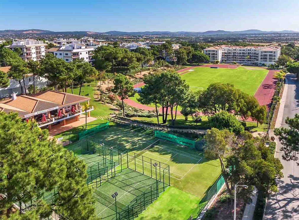 Aerial view of padel courts and an athletics stadium within the resort grounds.