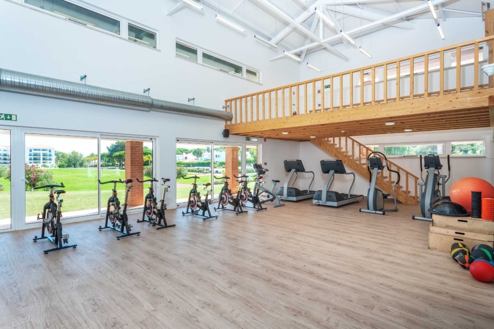 Bright gym with spin bikes, treadmills, and conditioning equipment for training camp workouts.