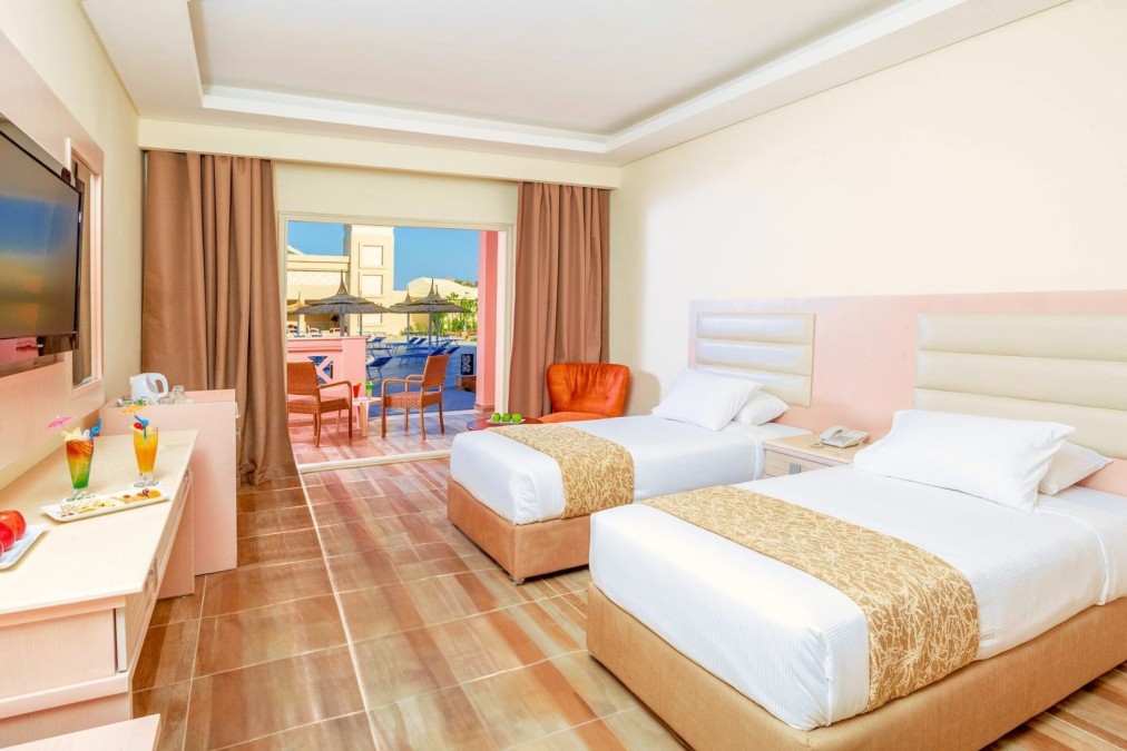 Guest room with twin beds, TV, and balcony view with outdoor seating