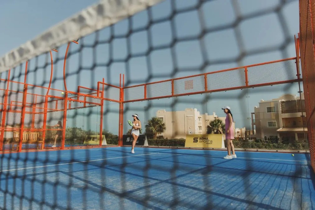 Overhead view of single blue tennis court with shadows cast