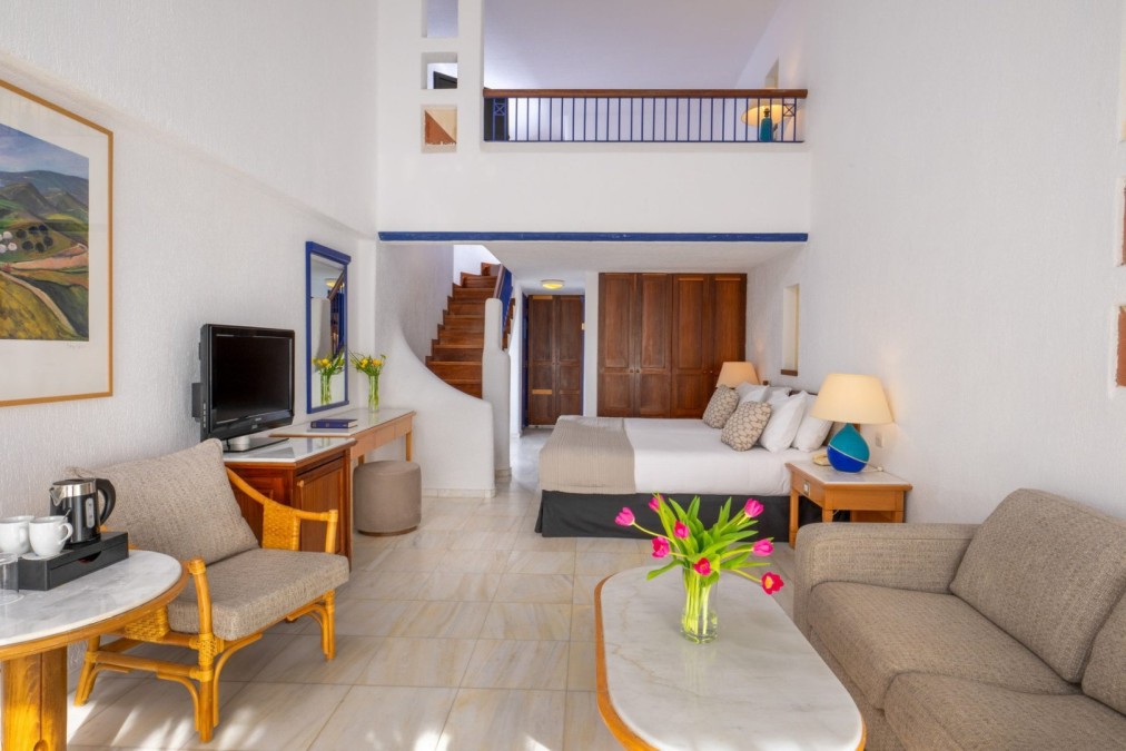 Bright duplex room with sofa, coffee table, bed, and balcony for athletes’ relaxation