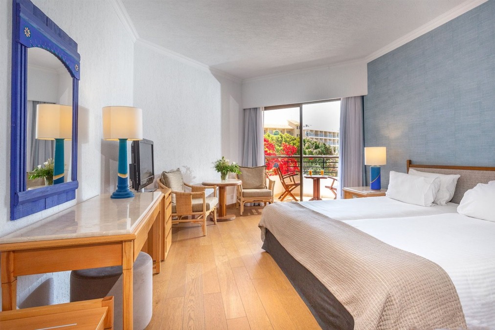 Modern guest room with blue accent wall, balcony, and workspace for sports camp guests