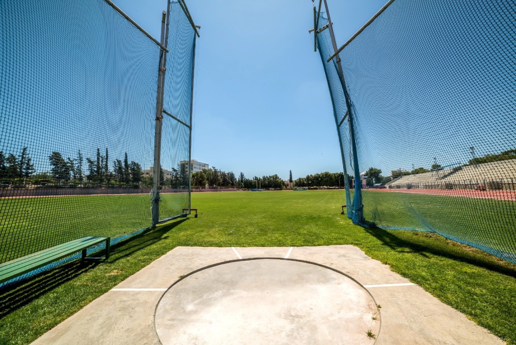 Hammer throw training area with safety nets and grass field under clear blue sky