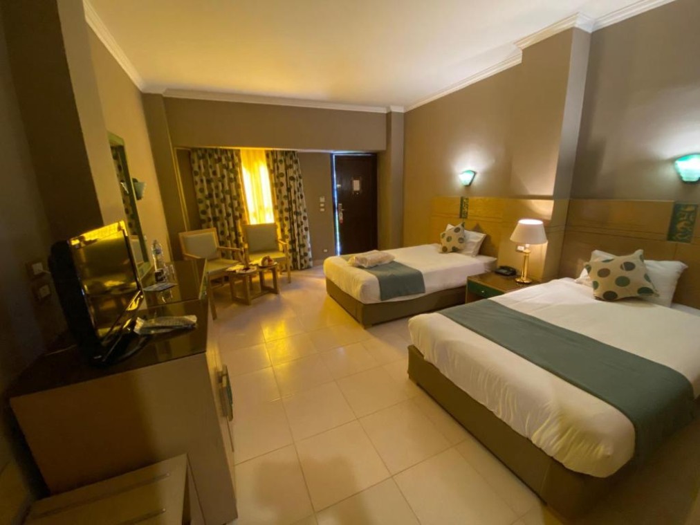 Twin room with two single beds, TV unit, and seating area with warm ambient lighting.