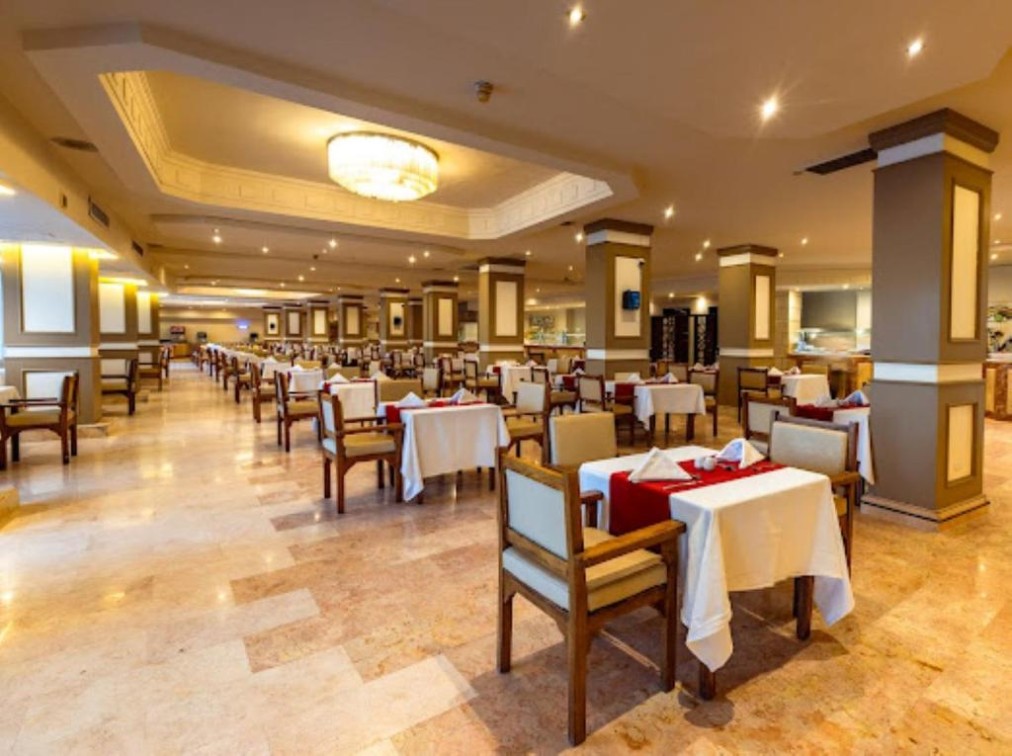 Large restaurant dining hall with set tables and warm lighting.
