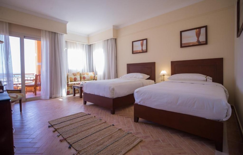 Bright twin-bed room with balcony seating and sofa for team stays.