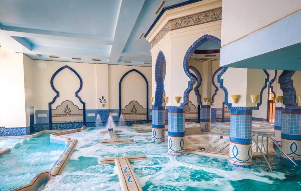Indoor spa pool with water jets, blue mosaic columns and arched walls for post-workout recovery