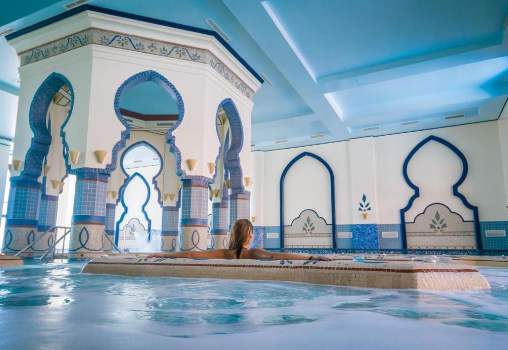 Indoor pool with blue mosaic arches and swimmer relaxing, suitable for training camp recovery