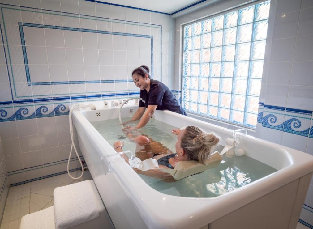 Hydrotherapy bath session with therapist assisting a guest, suitable for rehab and recovery