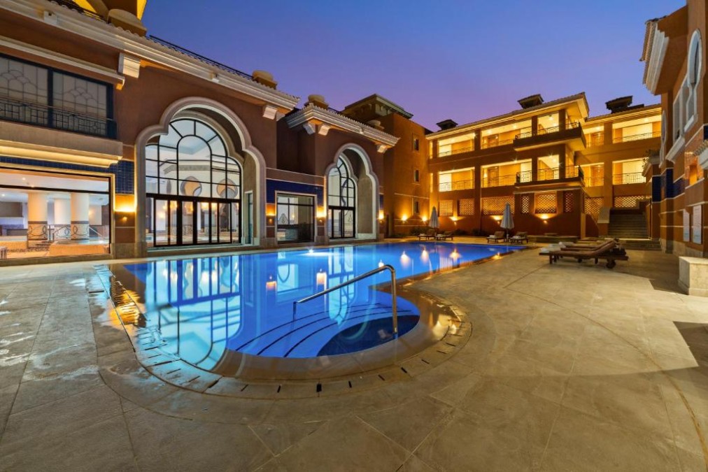 Evening pool courtyard with lit arches and loungers, calm space for winding down
