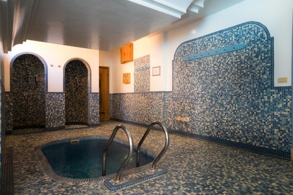 Small tiled jacuzzi/steam area with mosaic walls and shower alcoves for recovery and relaxation