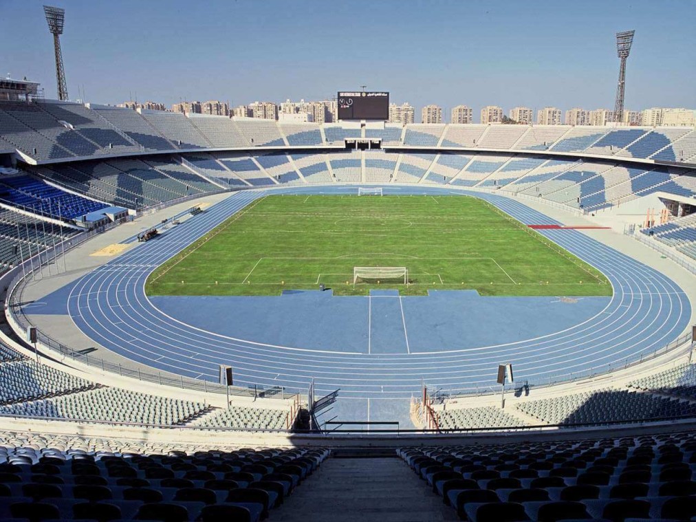 Empty athletics stadium with a blue running track surrounding a football pitch.