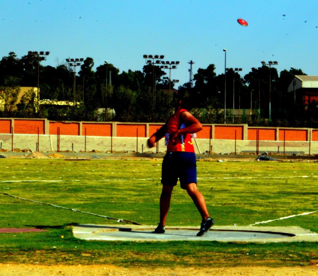 Athlete practicing discus throw from a throwing circle on an outdoor field.