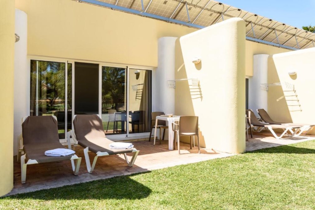 Private terrace with sun loungers and outdoor table outside guest rooms.