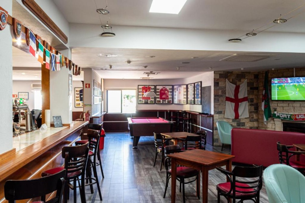 Sports bar lounge with pool table, seating and TV screens.