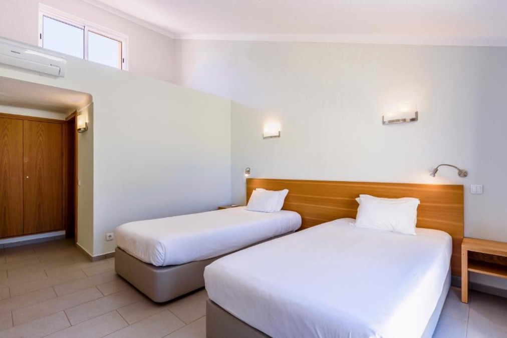Twin bedroom with two single beds, bedside table and wall lights.