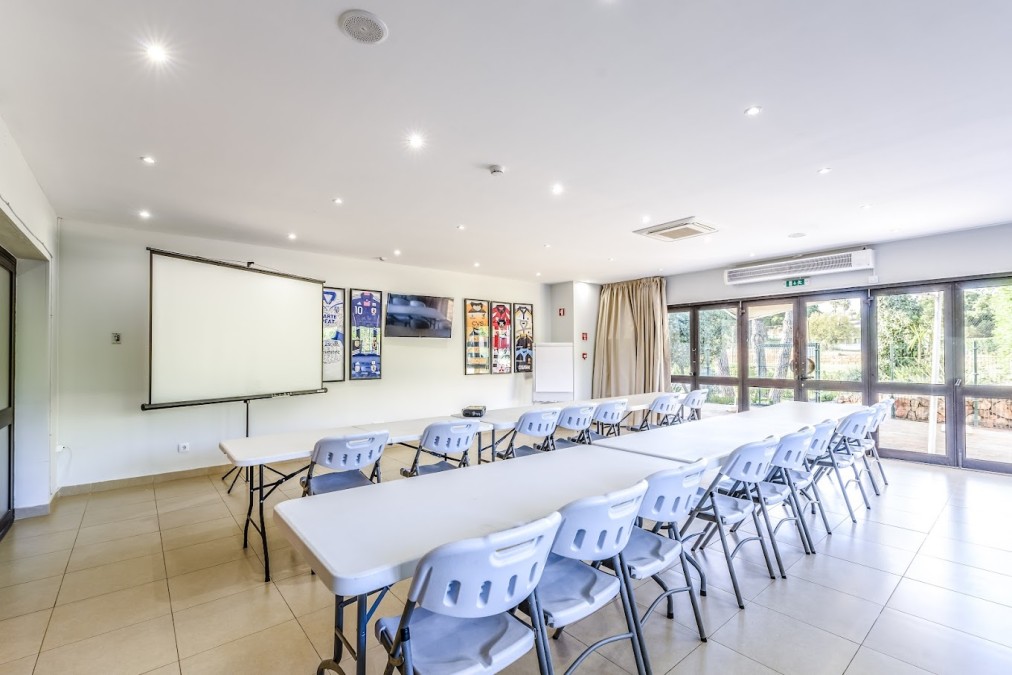 Meeting room with projector screen and tables set for team briefings.