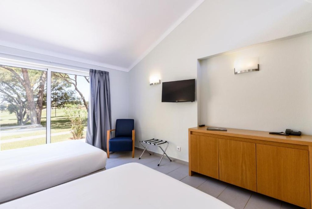 Twin guest room with TV, cabinet and large window overlooking the grounds.