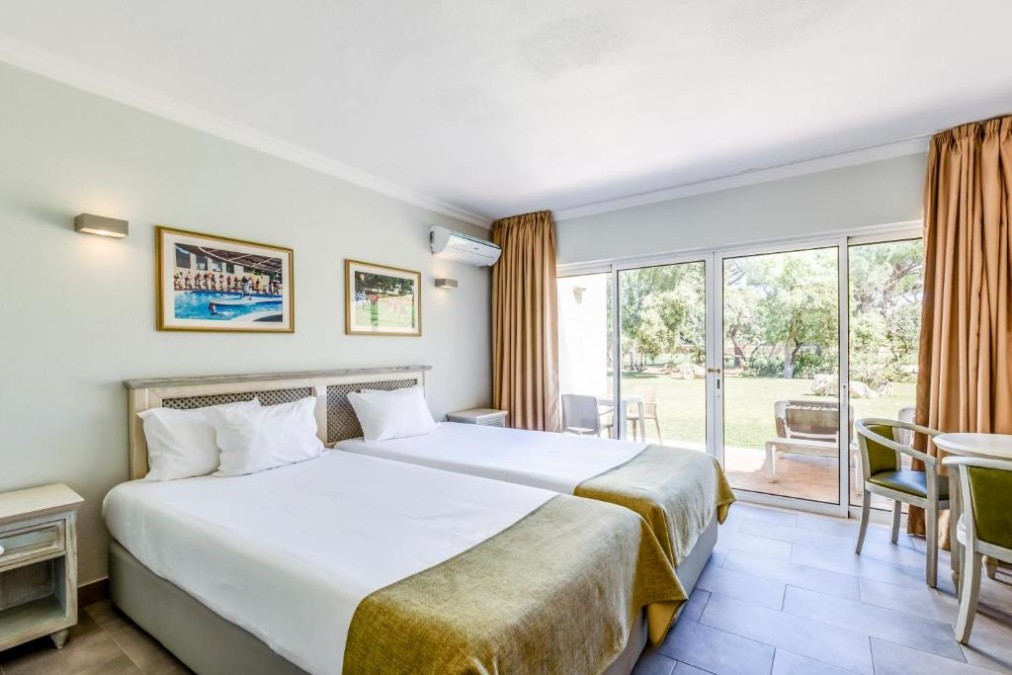 Twin bedroom with sliding doors to a terrace/garden, air conditioning and a small seating area.