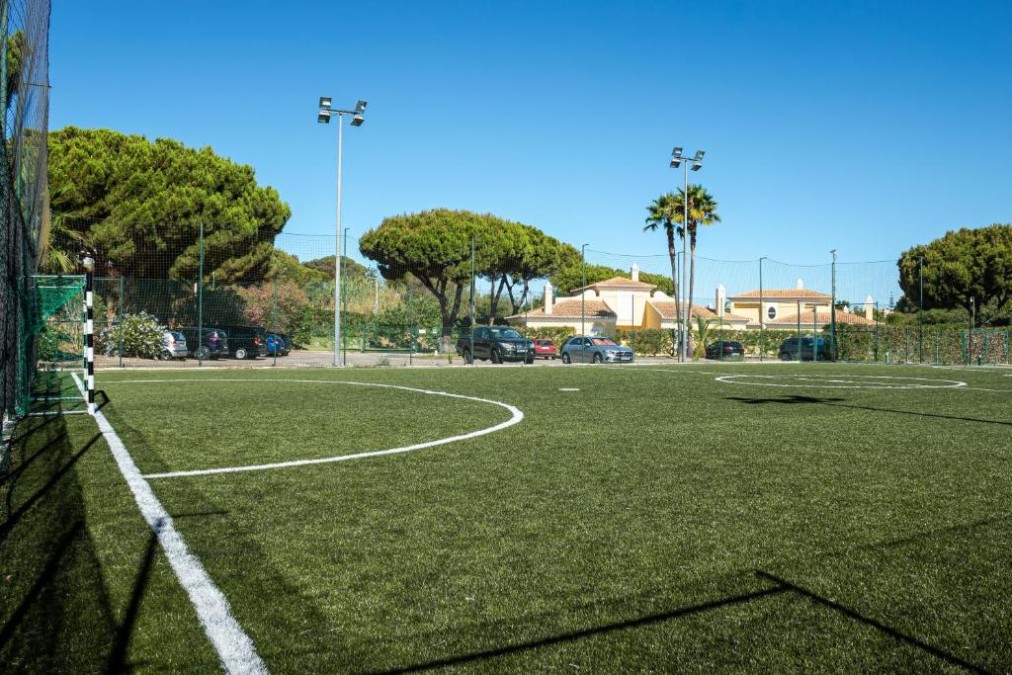 Fenced 5-a-side artificial turf football pitch with floodlights.