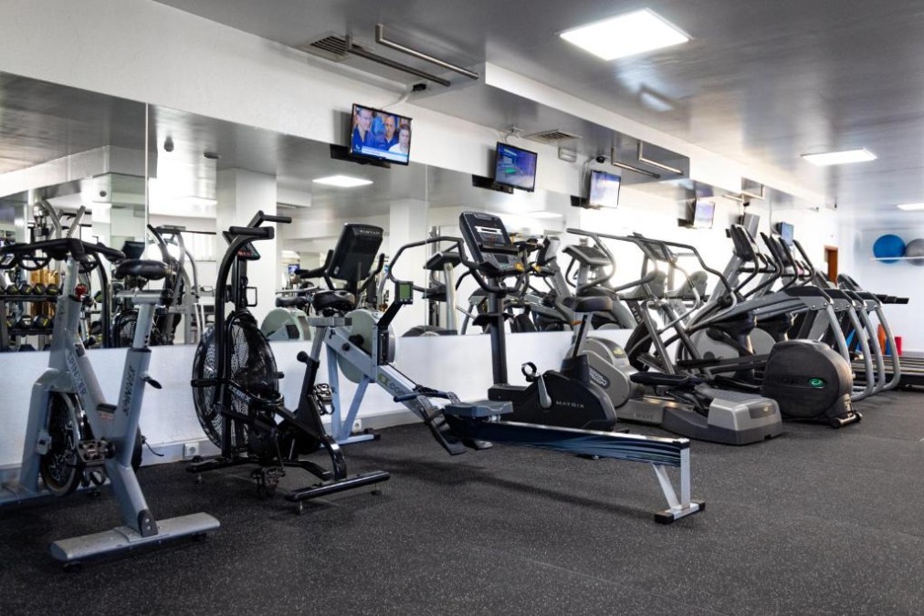Fitness room with cardio machines, rowing erg and mirrored wall.