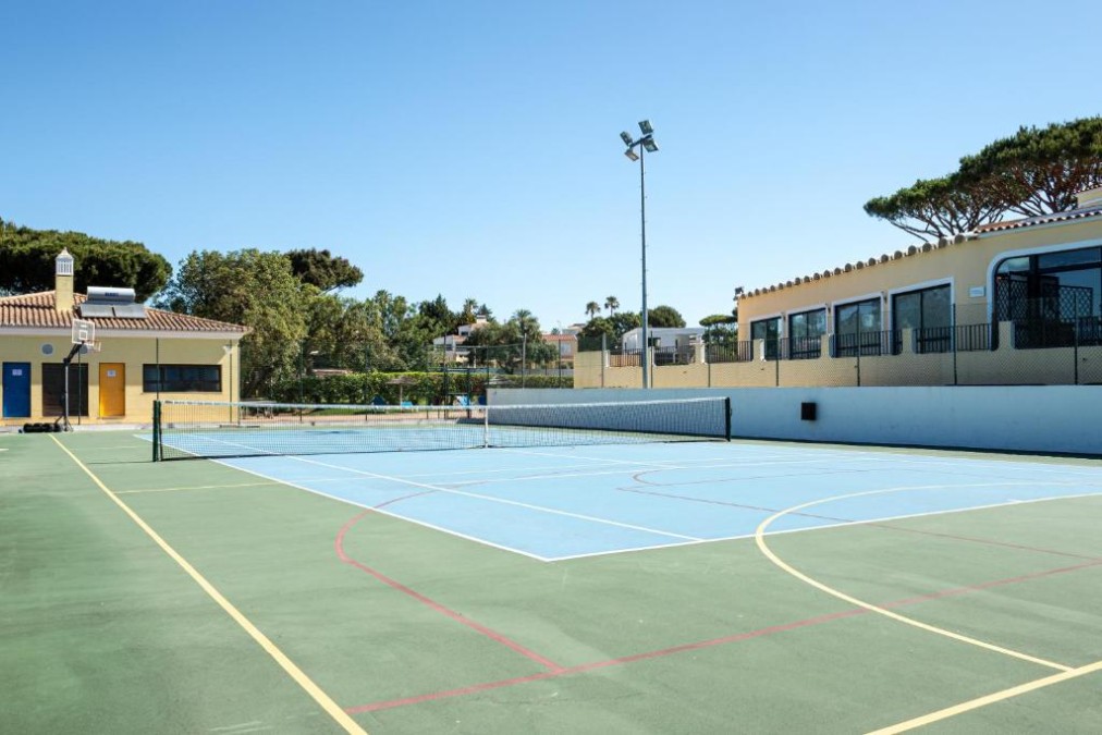 Outdoor multi-sport hard court with net and basketball hoop.