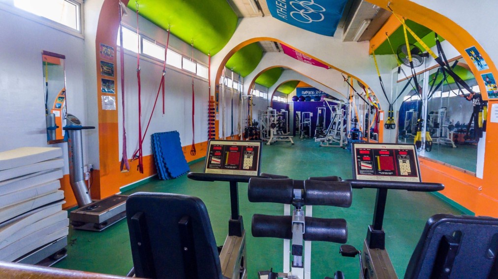 Colorful gym with cardio and strength equipment, mirrors and suspension straps.