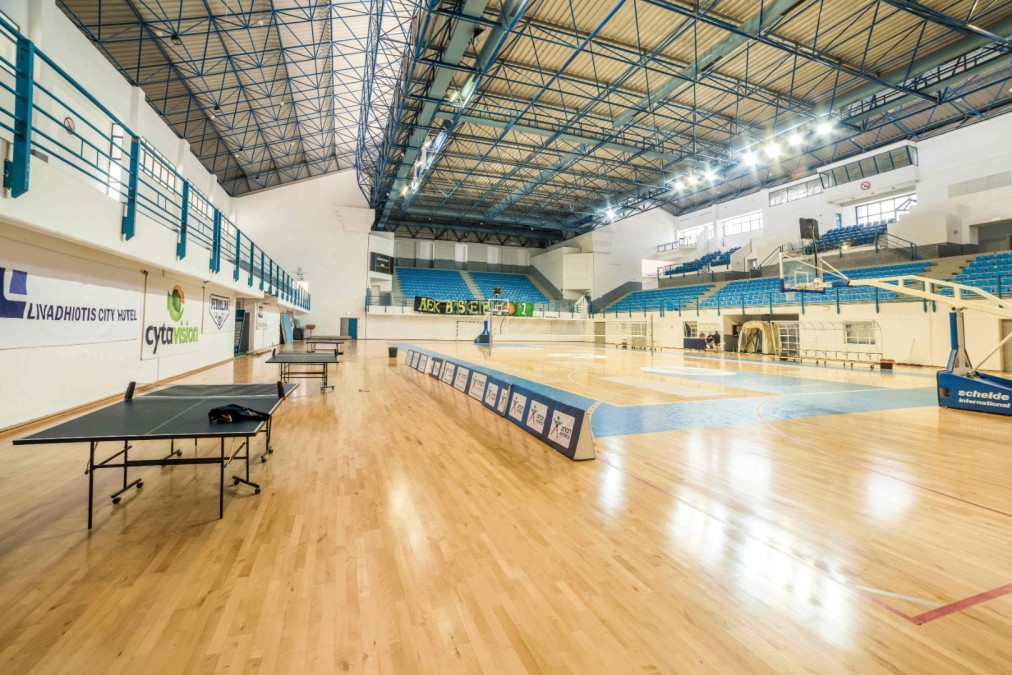 Indoor arena with basketball court, volleyball net and table tennis tables.