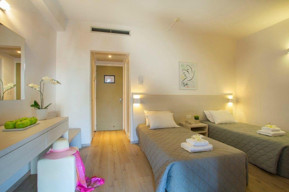 Cozy twin bedroom with soft lighting, light decor, and neatly arranged furniture