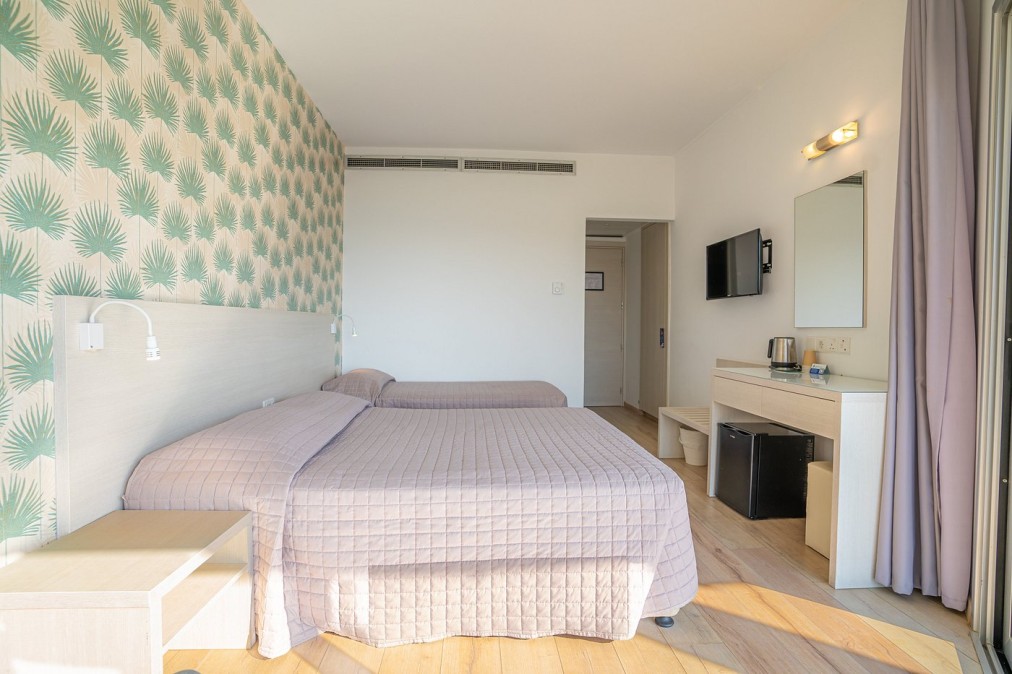 Bright hotel room with twin beds, pastel wallpaper, and modern furnishings