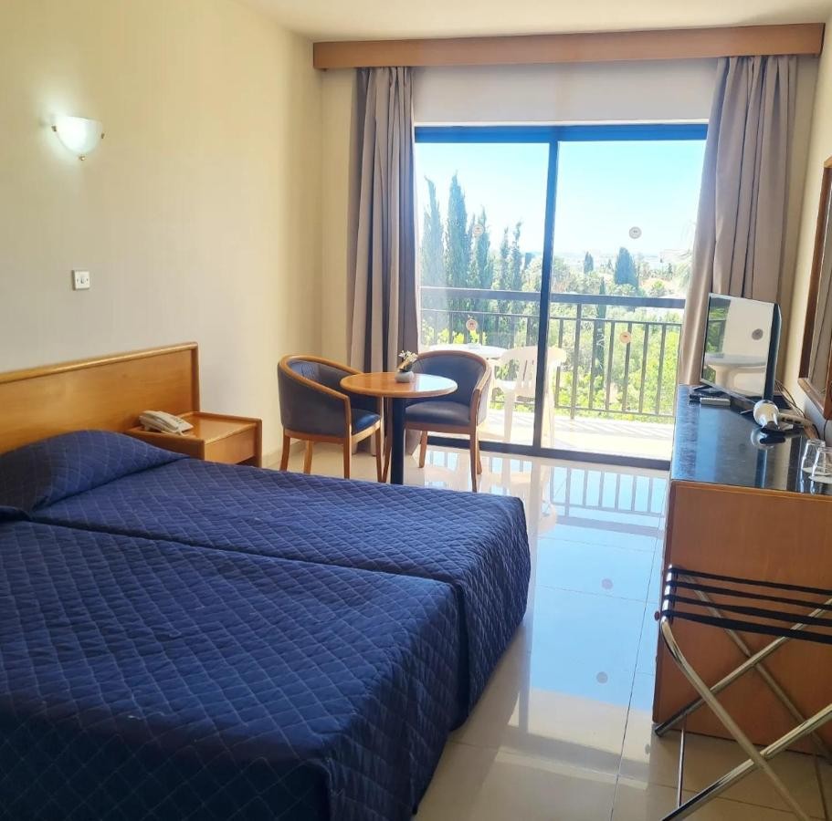 Twin guest room with balcony, TV, desk and seating area.