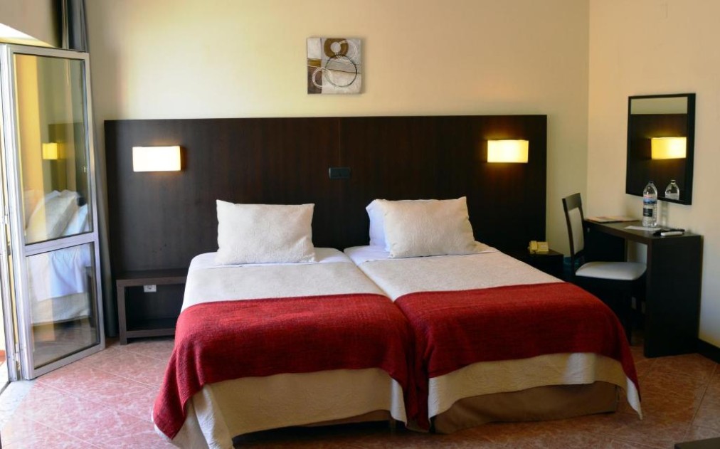 Twin room with desk, mirror and open balcony door.