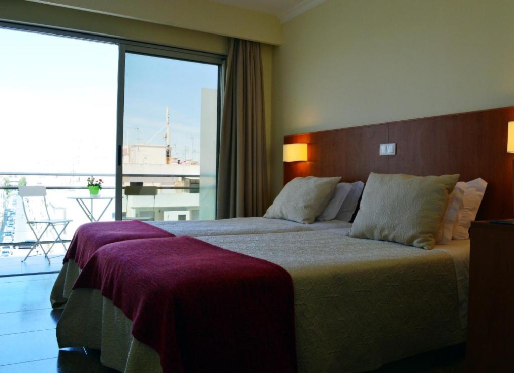 Twin room with balcony access and a small outdoor table and chairs.