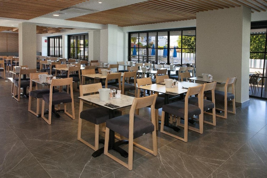 Bright restaurant dining area with neatly arranged tables, chairs and large windows.