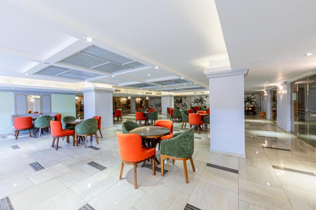 Indoor lounge with red and green chairs around tables on polished floor