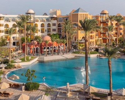 Resort with large lagoon-style pool, palm trees, and colorful architecture