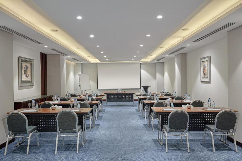 Conference room with classroom tables, water bottles, projector screen and flip chart for a coaching session