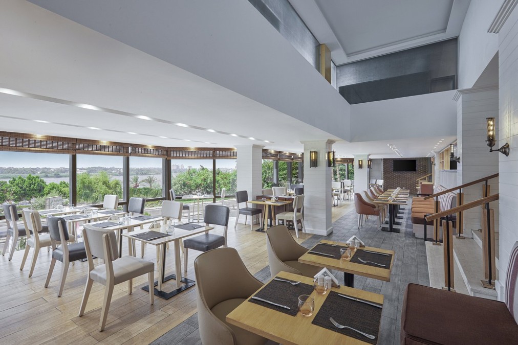 Hotel restaurant with set tables and large windows overlooking trees and river, for training camp meals