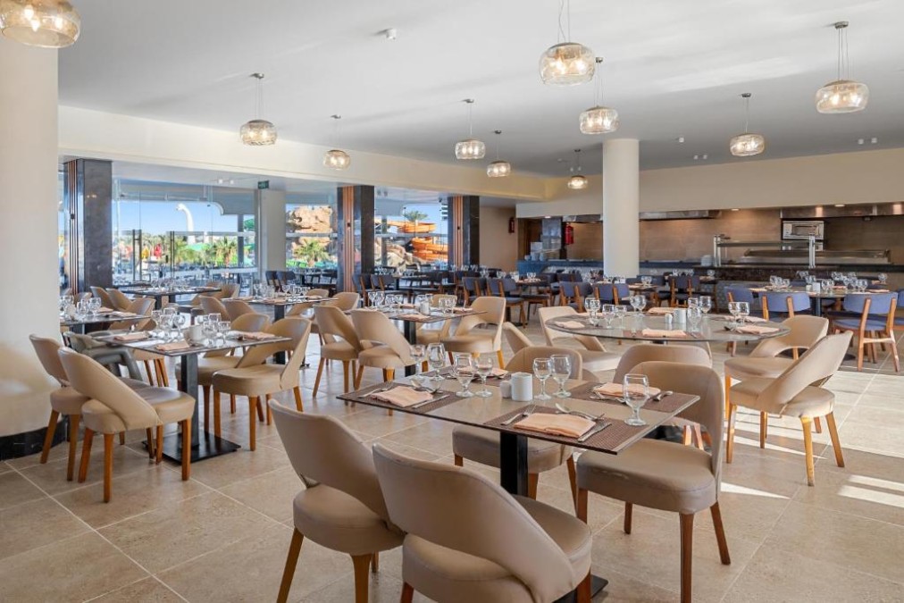 Buffet restaurant with set tables, glassware and open kitchen area.