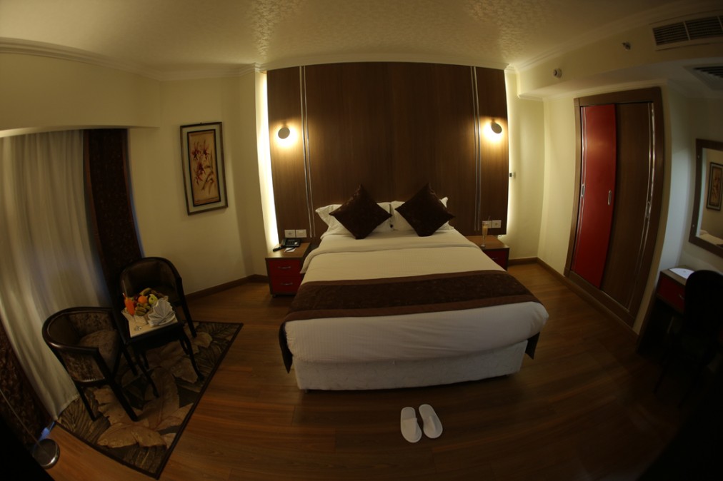 Double guest room with large bed, bedside tables, and slippers on the floor.