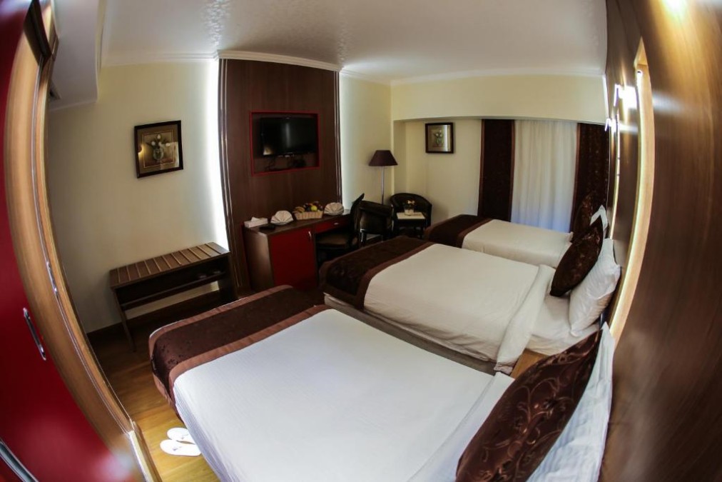 Twin guest room with two single beds, desk area, and wall-mounted TV.