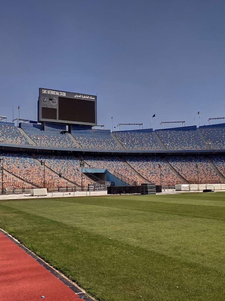 Pitch-side view of Cairo International Stadium seating and scoreboard above the stands.