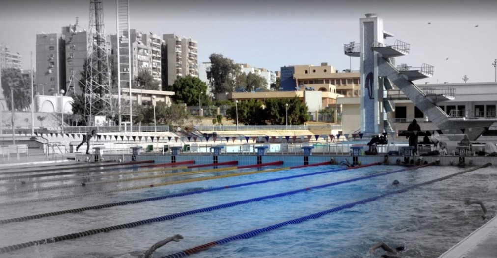 Outdoor pool lanes with a multi-level diving platform beside the deck.