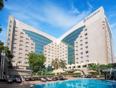 Hotel exterior with outdoor swimming pool, sun loungers, and terrace seating in the courtyard.
