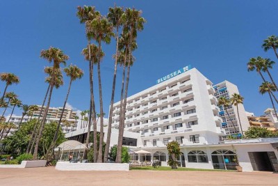 Exterior view of the hotel building framed by tall palm trees.