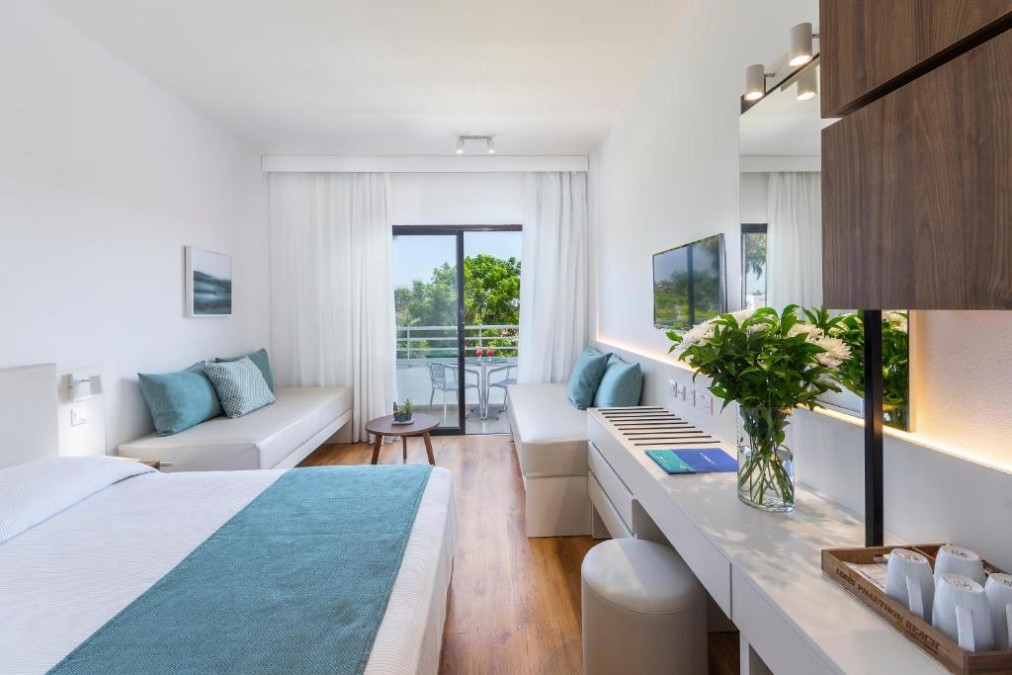 Bright guest room with desk, sofas and balcony view.